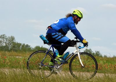 Vibrant cyclist riding on scenic trail with Bluebonnet Express branding, promoting outdoor biking adventures.