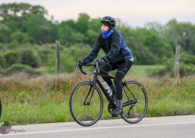 Comfortable woman riding a black bicycle along a scenic trail, promoting Bluebonnet Express bike tour.