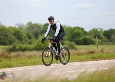 Smooth-riding cyclist on Texas outdoor trail with scenic greenery for Bluebonnet Express event.