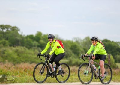 Bright yellow cycling jackets, two women riding bikes on scenic trail, outdoors, fitness, leisure, healthy lifestyle.