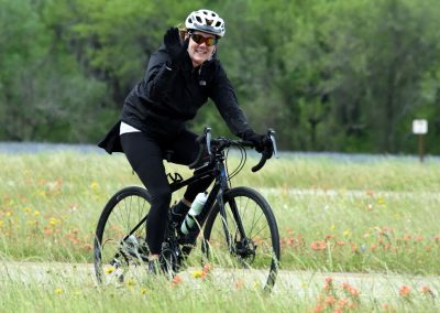 Vibrant cyclist enjoying a ride on the Bluebonnet Express trail with scenic wildflower fields.