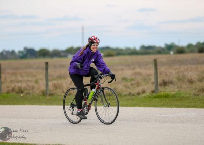 Vibrant woman cycling on scenic rural road, enjoying outdoor biking adventure in Texas.