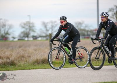 High-performance cycling on Bluebonnet Express trail with two cyclists in race gear.