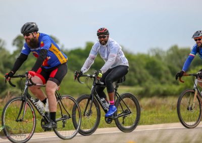 Brightly dressed cyclists riding through scenic countryside on Bluebonnet Express bike tour, enjoying outdoor adventure.
