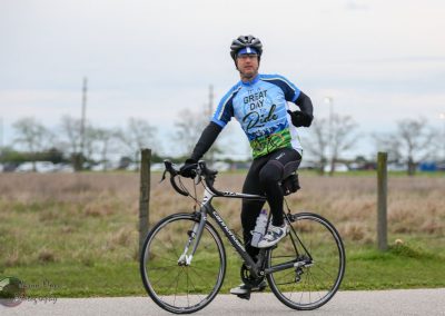 Bluebonnet express cycling event, man riding bike in outdoor race, cycling sportswear, scenic trail, Texas countryside, active rider SEO.