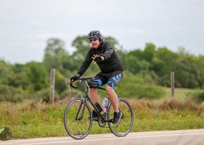 Bright male cyclist riding on scenic trail with lush greenery, promoting Bluebonnet Express bike services.