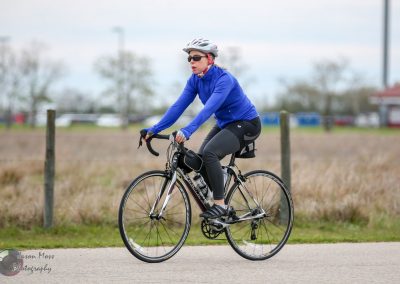 Comfortable women cyclist riding a bike on a trail with Bluebonnet Express branding.
