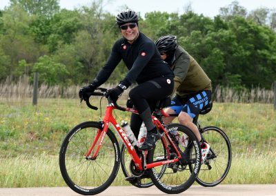 Man riding a red Trek road bike on a rural trail with a companion, enjoying outdoor cycling.