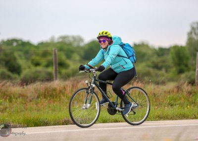 Bright blue cyclist jacket on woman riding a bike outdoors, enjoying an eco-friendly ride.