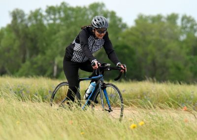 Bright woman cycling through wildflower field on Bluebonnet Express bike trail, enjoying nature and outdoor adventure.