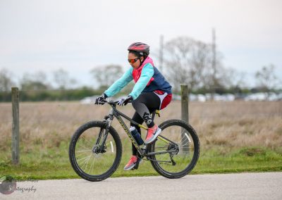 Young girl riding a mountain bike in outdoor trail, wearing helmet and sports gear, enjoying cycling adventure.