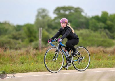 Pink helmet, girl riding blue road bike on rural trail, outdoor cycling, fitness, healthy lifestyle.