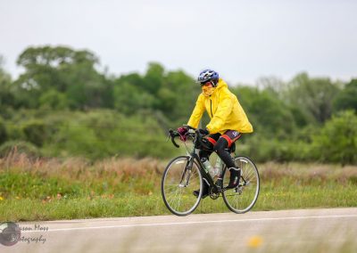 Bright yellow cycling jacket on cyclist riding a bike outdoors in nature.