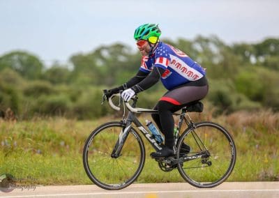 High-performance cyclist riding a bike on outdoor trail during daytime, promoting Bluebonnet Express bike services.