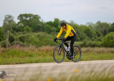 Bright yellow cyclist jacket on a black road bike during a ride in nature.