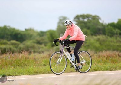 Bright woman cycling outdoors on a bike trail for Bluebonnet Express event.