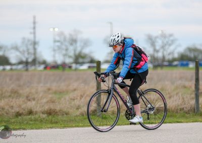 Bright blue and pink bike trail cycling gear for women near Texas stretching grass.