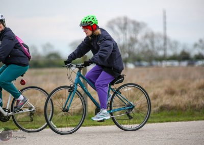Vibrant women cycling outdoors on a cloudy day, riding bikes through open countryside for exercise and leisure.