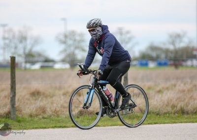 High-performance cyclist riding on a trail with a blue bike and cycling gear, promoting Bluebonnet Express.