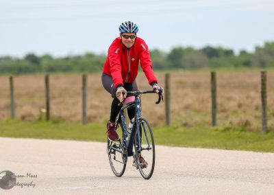 Bright male cyclist riding bikes on scenic outdoor trail, wearing red jacket and helmet for Bluebonnet Express.