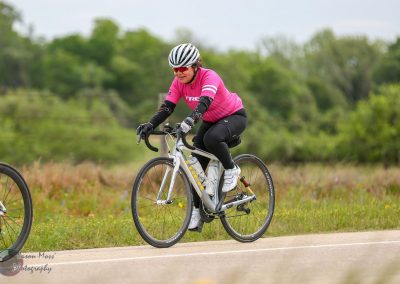 Vibrant woman riding an e-bike on a scenic trail during daytime, promoting Bluebonnet Express cycling tours.