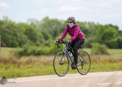 Vibrant cyclist riding a bike on scenic rural trail, promoting Bluebonnet Express cycling tours.