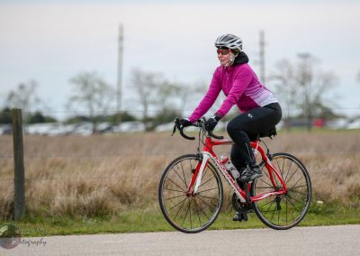 Comfortable woman riding a red hybrid bike outdoors, pursuing a cycling activity, during daytime.
