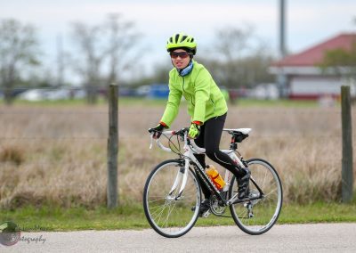 Bright woman cycling outdoors in neon green jacket and helmet on a scenic bike ride.