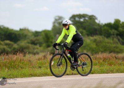 High-visibility cycling rider on Bluebonnet Express biking trail, outdoors and scenic.