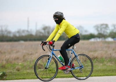 Bright yellow cycling jacket with rider on road bike in outdoor setting.