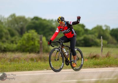 Vibrant cyclist riding on rural road, promoting Bluebonnet Express long-distance bike ride event.