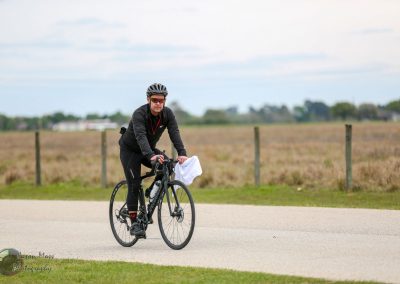 Vegan cyclist riding on a scenic rural bike trail with a wide open field background.