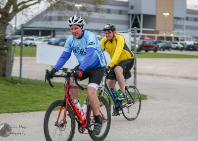 Bright blue and yellow cycling jerseys featuring Bluebonnet Express logo, two cyclists enjoying a ride together.
