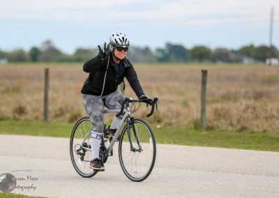 1. Female cyclist riding a road bike during daytime in open countryside.