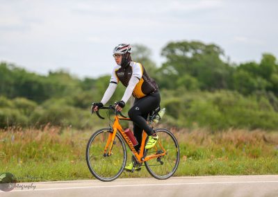 Bright orange Specialized road bike on a scenic rural trail during daytime.