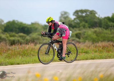 Vast cycling landscape with a female cyclist riding on a scenic rural road, showcasing Bluebonnet Express biking adventure.