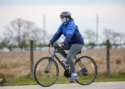 Comfortable woman riding e-bike on scenic trail during daytime, promoting Bluebonnet Express cycling event.
