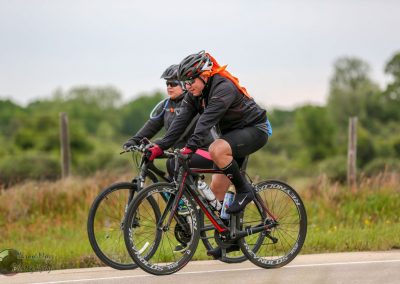 Fast cyclists riding on a rural road, promoting Bluebonnet Express bike tours and cycling adventures.