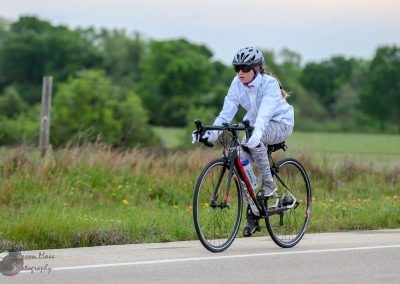 Cyclist riding a road bike on scenic trail, promoting Bluebonnet Express biking adventures.