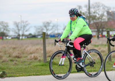 Bright female cyclist wearing neon green jacket on a bike trail.