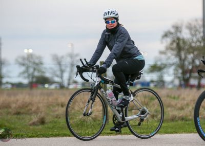 Bright woman cycling outdoors on a scenic trail, promoting Bluebonnet Express bike rides and eco-friendly transportation.