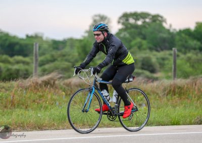 1. Man riding a Bluebonnet Express electric bike on a scenic outdoor trail.