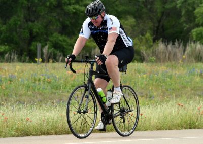 Bright woman cycling on a trail in a scenic outdoor setting, promoting Bluebonnet Express cycling event and adventure tourism.