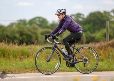 Vibrant cyclist riding the Bluebonnet Express bike trail in Texas with scenic nature backdrop.