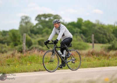 Smooth road cyclist riding on a scenic countryside route with lush greenery and blue skies.