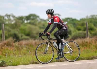 Bright cyclist riding bluebonnet express bike on scenic rural route in Texas, promoting outdoor adventure and cycling.