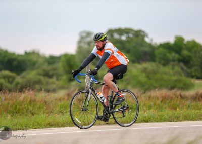 Man riding a bicycle on a scenic rural road, promoting outdoor adventure and eco-friendly transportation.