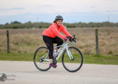 Bright woman cycling on a scenic rural path with Bluebonnet Express bike, enjoying outdoor fitness and adventure.