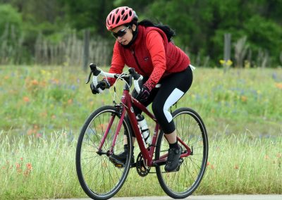 Bright pink bicycle on scenic trail with cyclist in red gear and helmet.