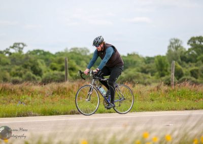 Cyclist riding on scenic rural road, promoting eco-friendly transportation.
